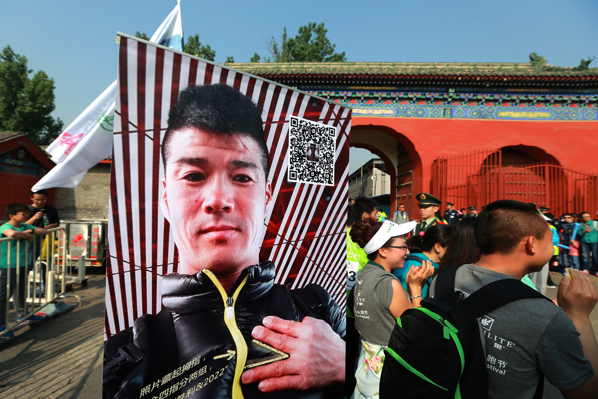 本次安利长跑节场地毗邻古风红墙建筑，现场摆放印有“胜利&2022”字样、互动二维码的人物宣传展架，周边聚集多名身着印有“跑节”“LITE 莱”标识活动服的参与者，现场氛围热烈活力，彰显安利运动类活动的积极风貌。