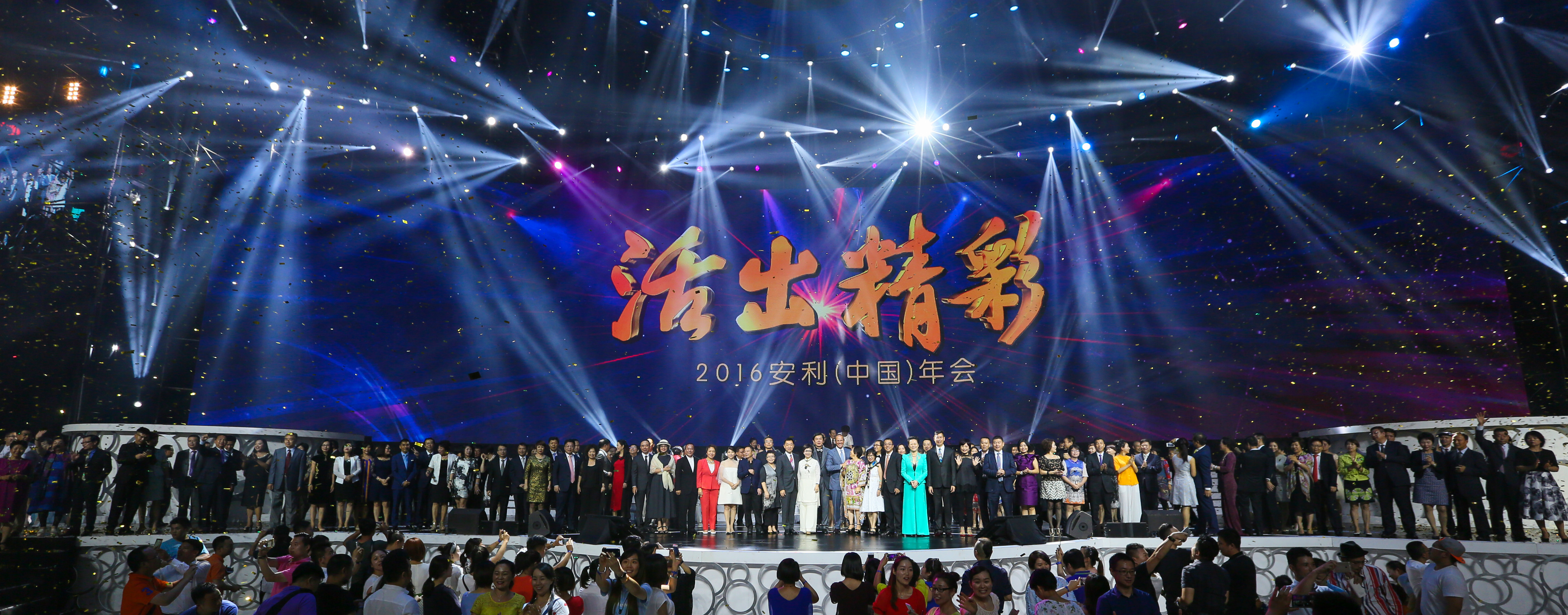 本次2016安利（中国）年会以“活出精彩”为主题，现场舞台灯光绚丽璀璨，金色彩屑在空中飞扬，众多安利伙伴整齐列队站在舞台之上，台下观众纷纷举机记录，氛围热烈隆重，尽显昂扬向上的品牌活力与伙伴共聚的喜悦氛围。