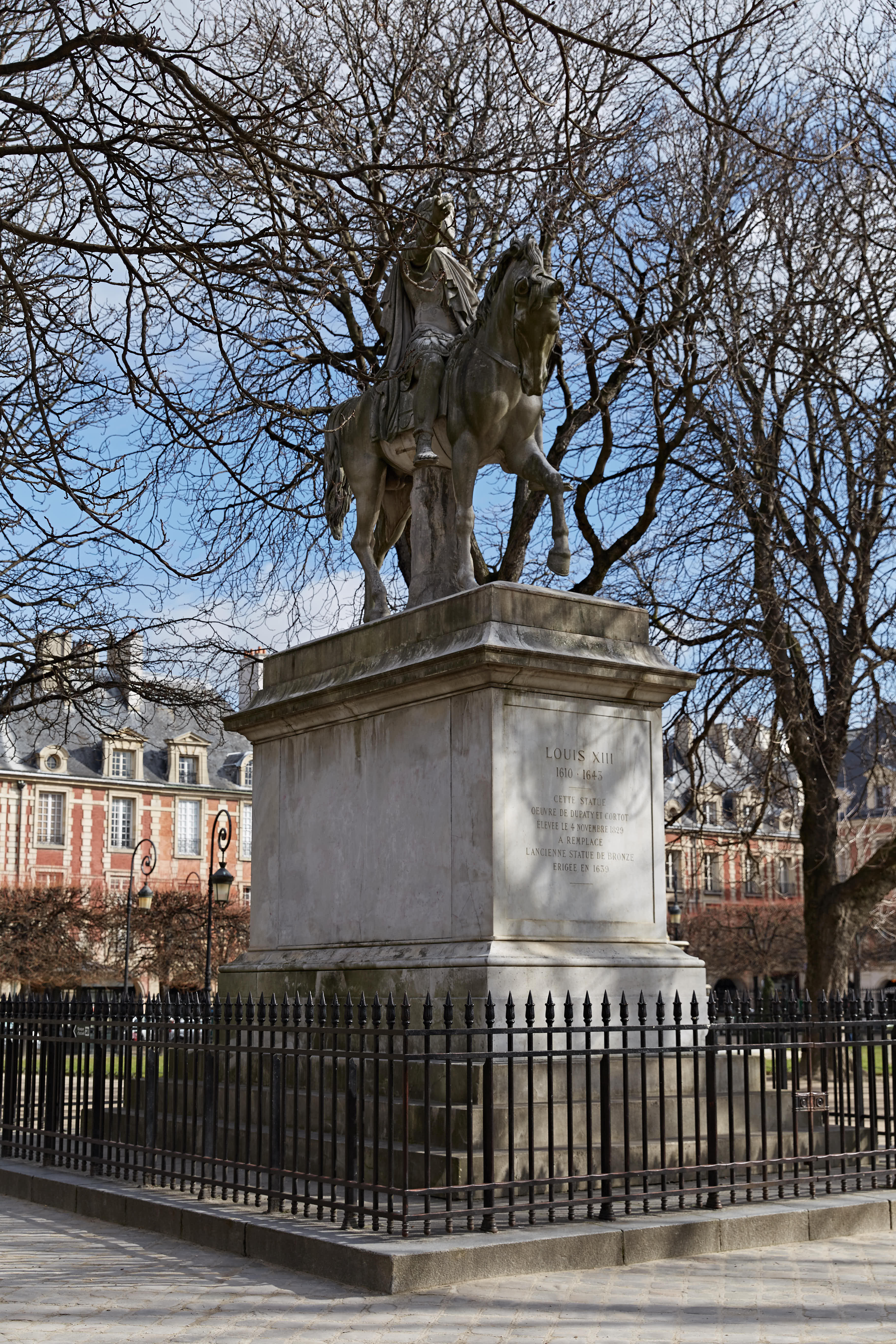 本场景为安利法国研讨会游学打卡点位，雕像基座刻有核心文字“LOUIS XIII 1610-1645”，石质骑马雕像庄重古朴，外围设黑色铁艺围栏，背景是典雅法式复古建筑，澄澈蓝天映衬下氛围开阔肃穆，人文底蕴浓厚。