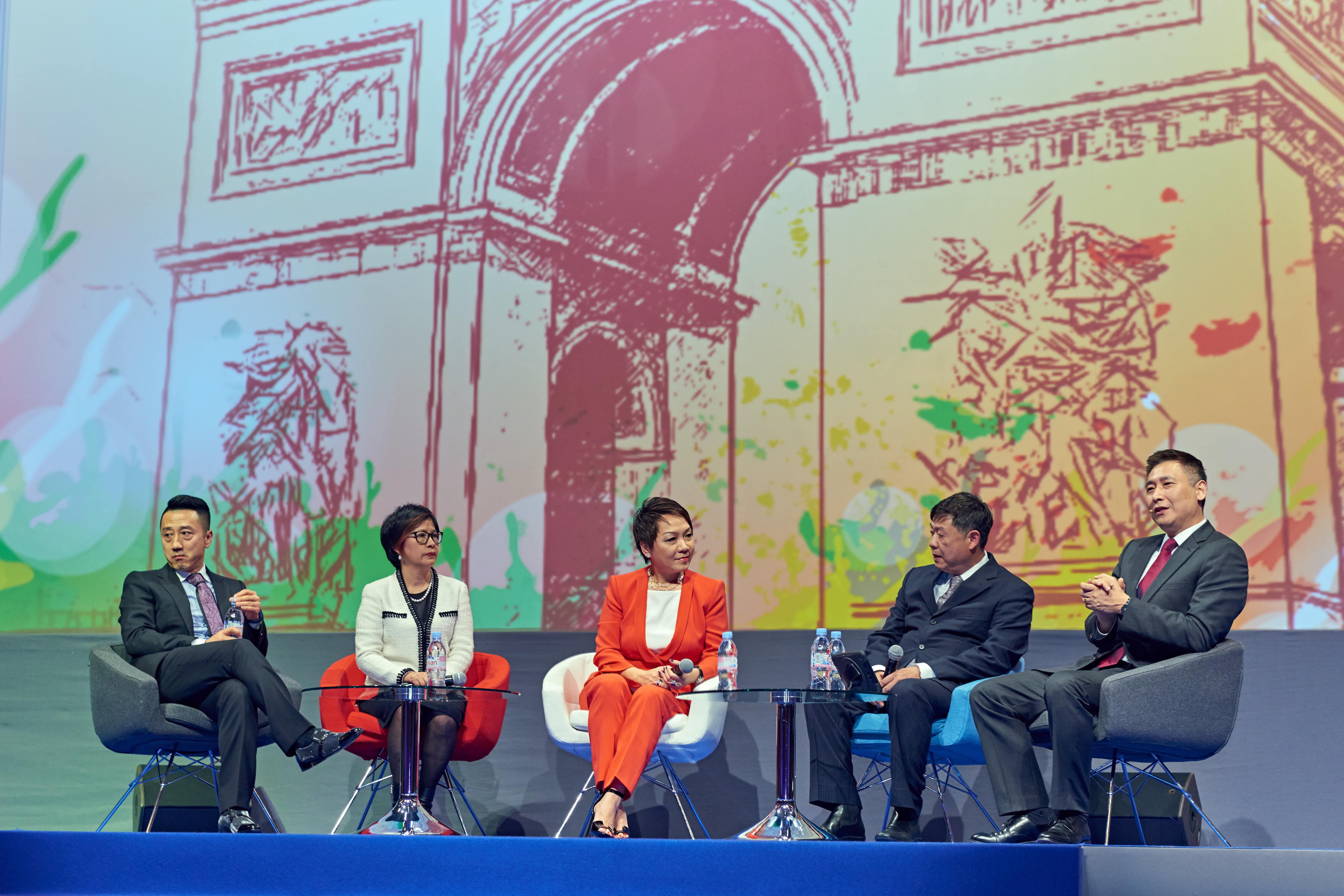 画面为安利研讨会圆桌对话环节，五位企业嘉宾落座舞台交流区，围绕相关议题开展深度交流分享，背景为彩绘风格地标艺术画面，现场氛围专业热烈，充分展现安利活动高端交流质感与积极探索的品牌风貌。