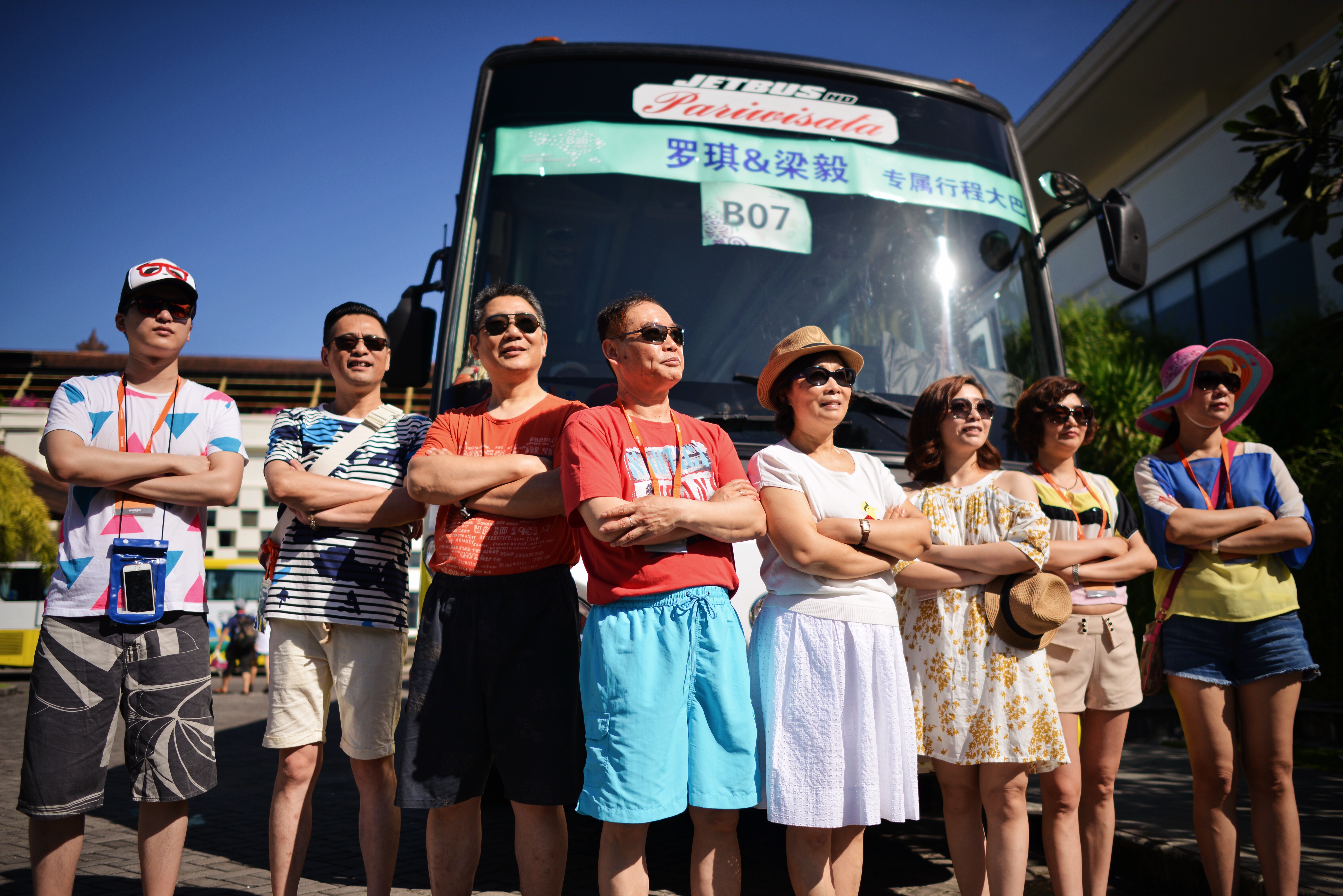 晴好日光下，8位身着休闲度假装束的安利营销伙伴，整齐站在标有“罗琪&梁毅 专属行程大巴”“B07”的大巴车前，大家抱臂而立、神态轻松昂扬，氛围明快活力，尽显本次出游活动的愉悦氛围与伙伴们的饱满状态。