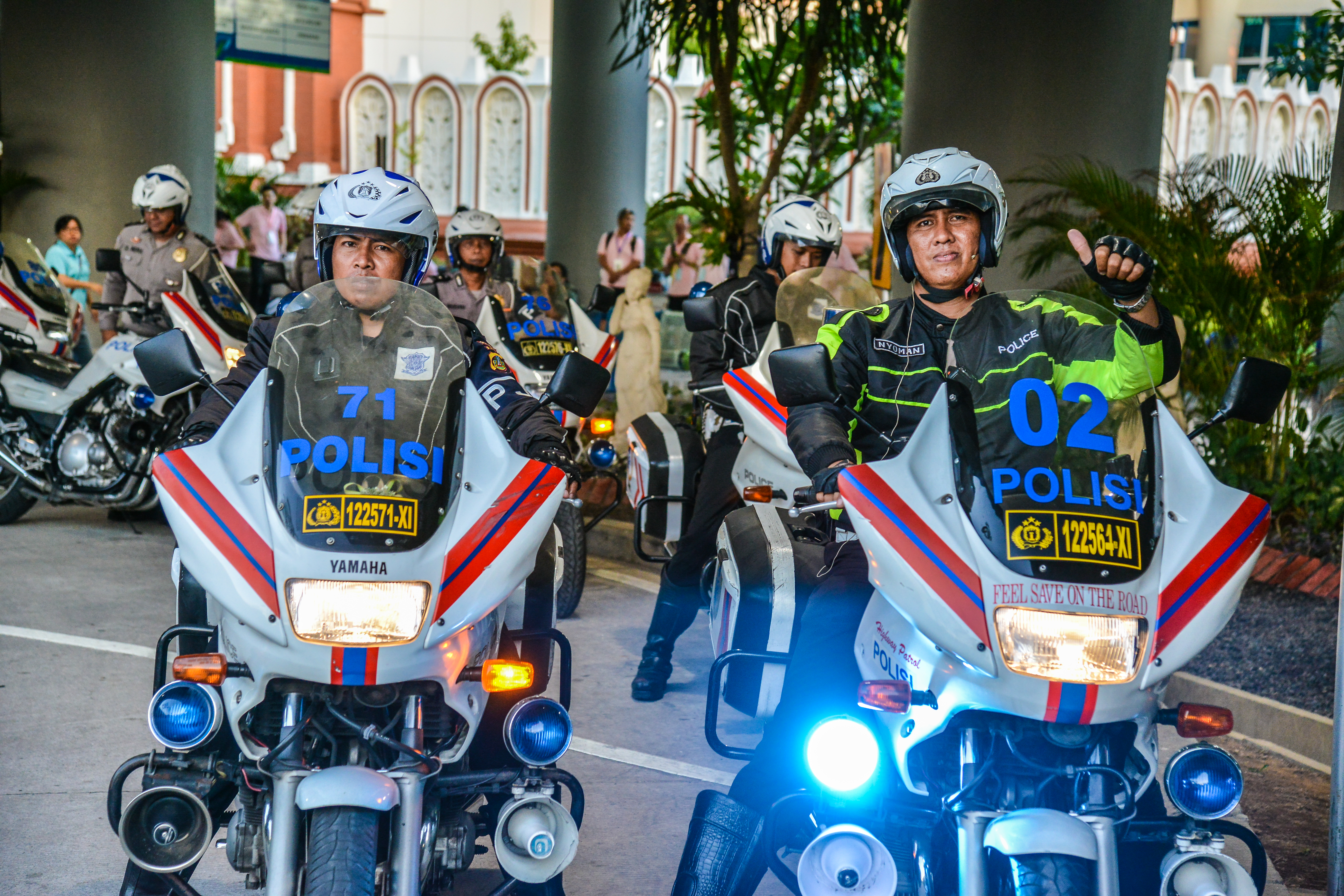画面中多位印尼警务人员驾乘印有“POLISI”标识的警用摩托整齐列队，警摩标识清晰、装备齐全，有警员友好竖起拇指，状态专业饱满，全力为安利品牌活动提供出行安全护航保障，现场秩序井然，尽显可靠的支持力量。
