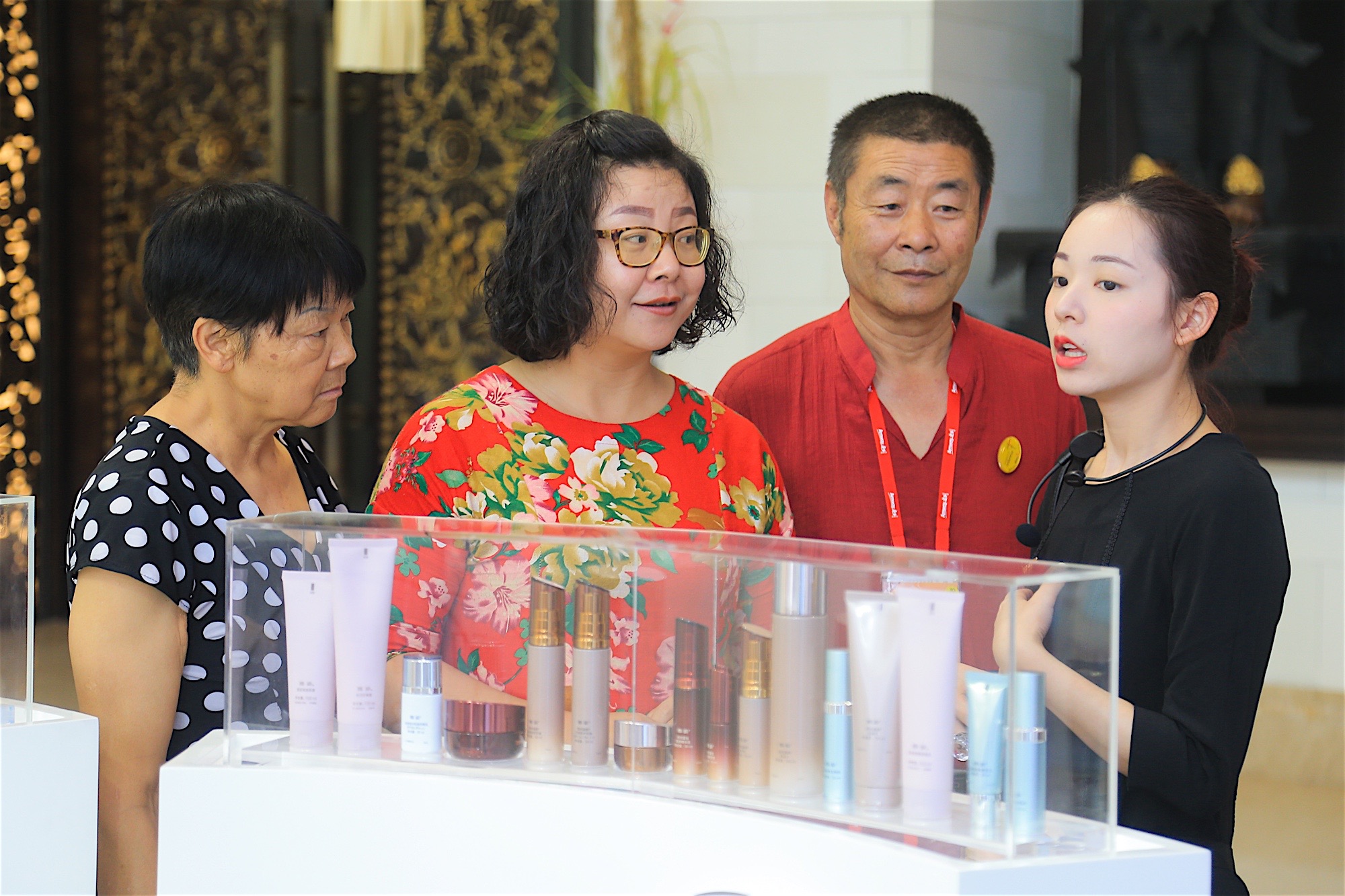 安利活动护肤产品展区内，佩戴耳麦的工作人员正向几位来宾细致讲解展柜中陈列的安利护肤系列产品，来宾们认真聆听、关注产品细节，现场氛围专业融洽，充分展现安利品牌的优质服务与产品魅力。
