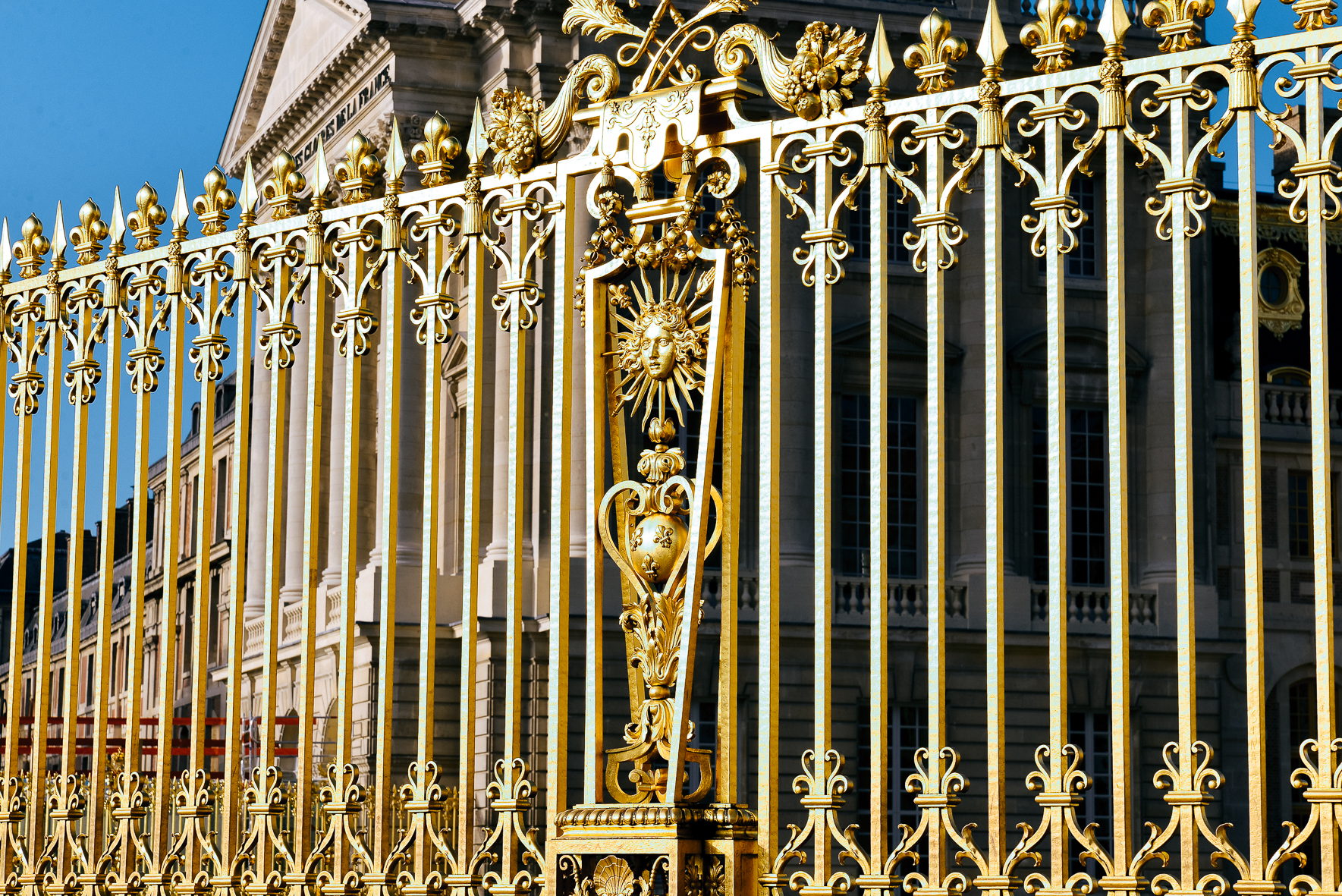 晴朗蓝天映衬下，刻有“ACADEMIE DE FRANCE”字样的古典建筑前，凡尔赛宫鎏金栅栏工艺精湛，雕花繁复精美，标志性太阳王纹饰熠熠生辉，整体氛围华贵大气，是安利精英海外研讨行程的特色打卡场景。