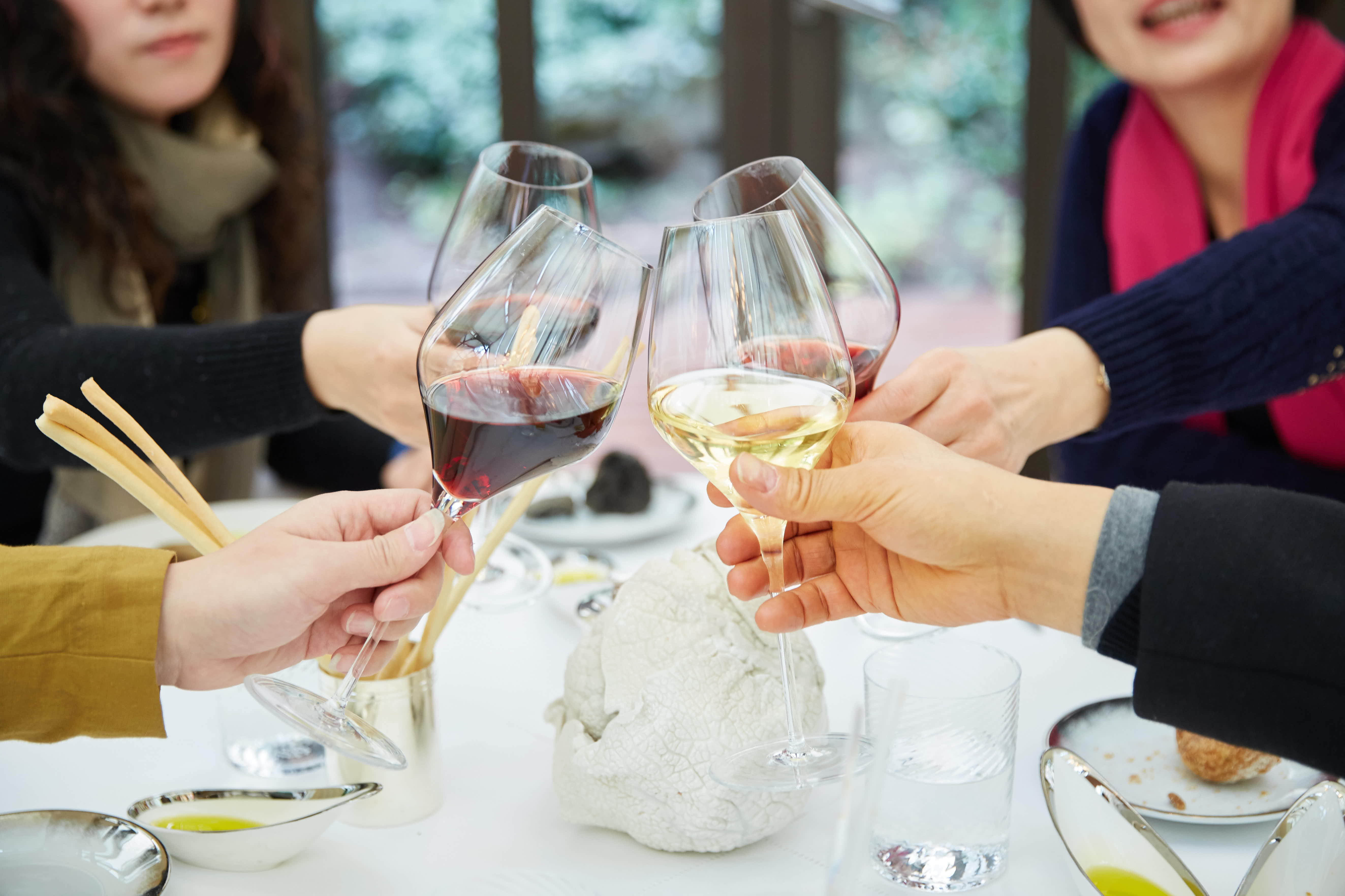 本次安利线下活动配套聚餐环节中，多位伙伴共同举杯碰杯，杯中盛有红、白葡萄酒，桌面摆放着精致餐食与餐具，整体氛围轻松热烈、温馨融洽，尽显伙伴间的深厚情谊，彰显安利温暖有爱的团队文化。