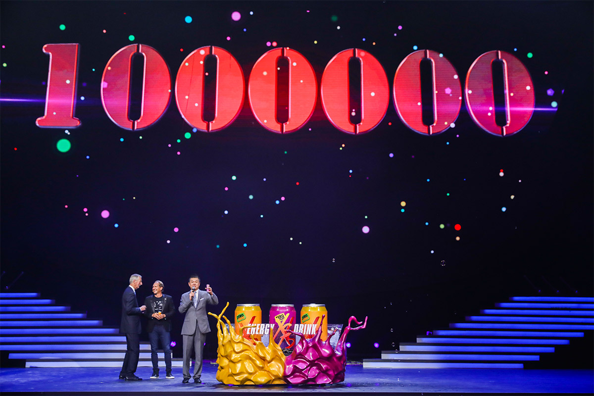 活动舞台背景设有醒目的红色“1000000”字样，三位嘉宾站立于舞台区域，前方摆放着XS ENERGY DRINK主题创意展示装置。现场灯光绚烂、氛围隆重热烈，尽显安利XS产品取得百万销量的喜人成果。