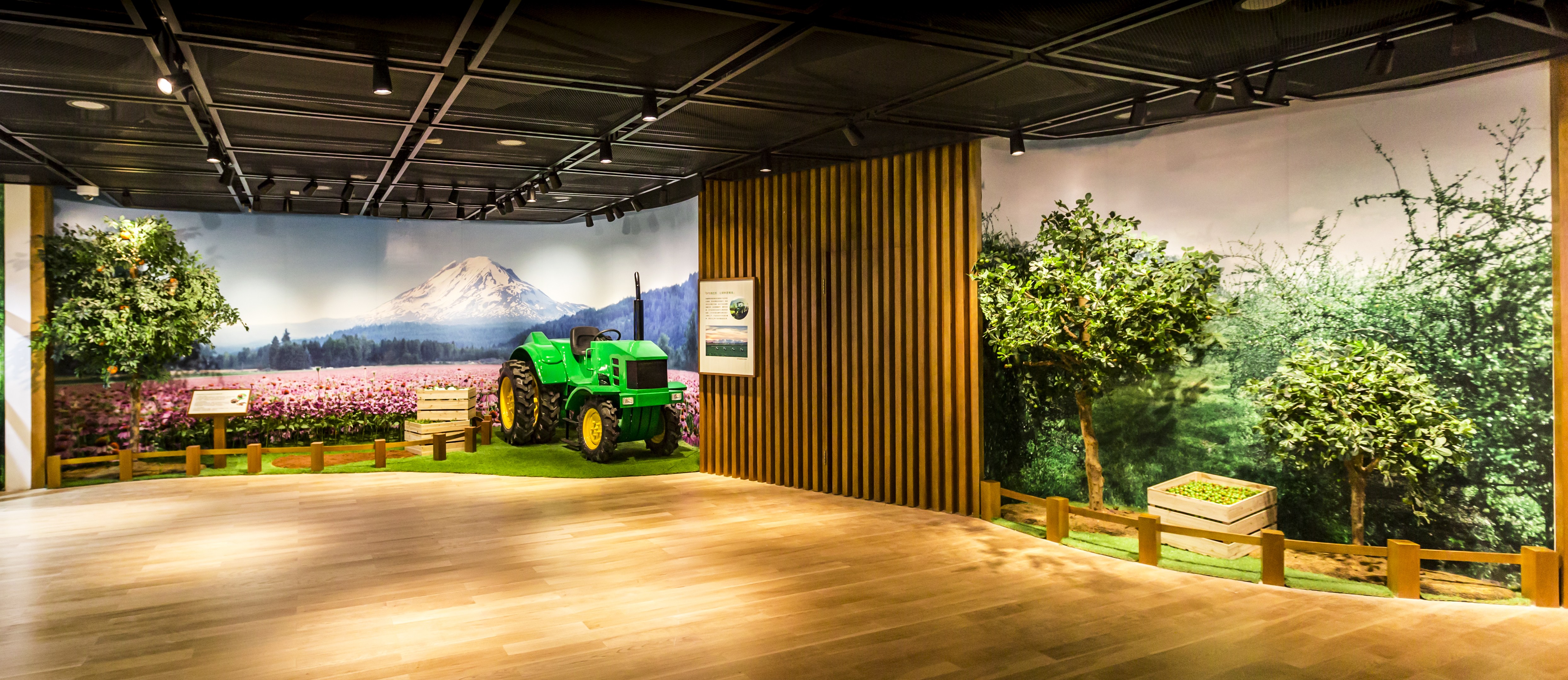 本展区采用实景还原形式打造，设置绿色农机模型、雪山花田背景墙、仿真果林造景与科普展板，生动展现安利原料有机种植风貌，传递品牌对原料源头的严苛品控，整体环境整洁明亮，凸显自然健康的品牌内核。