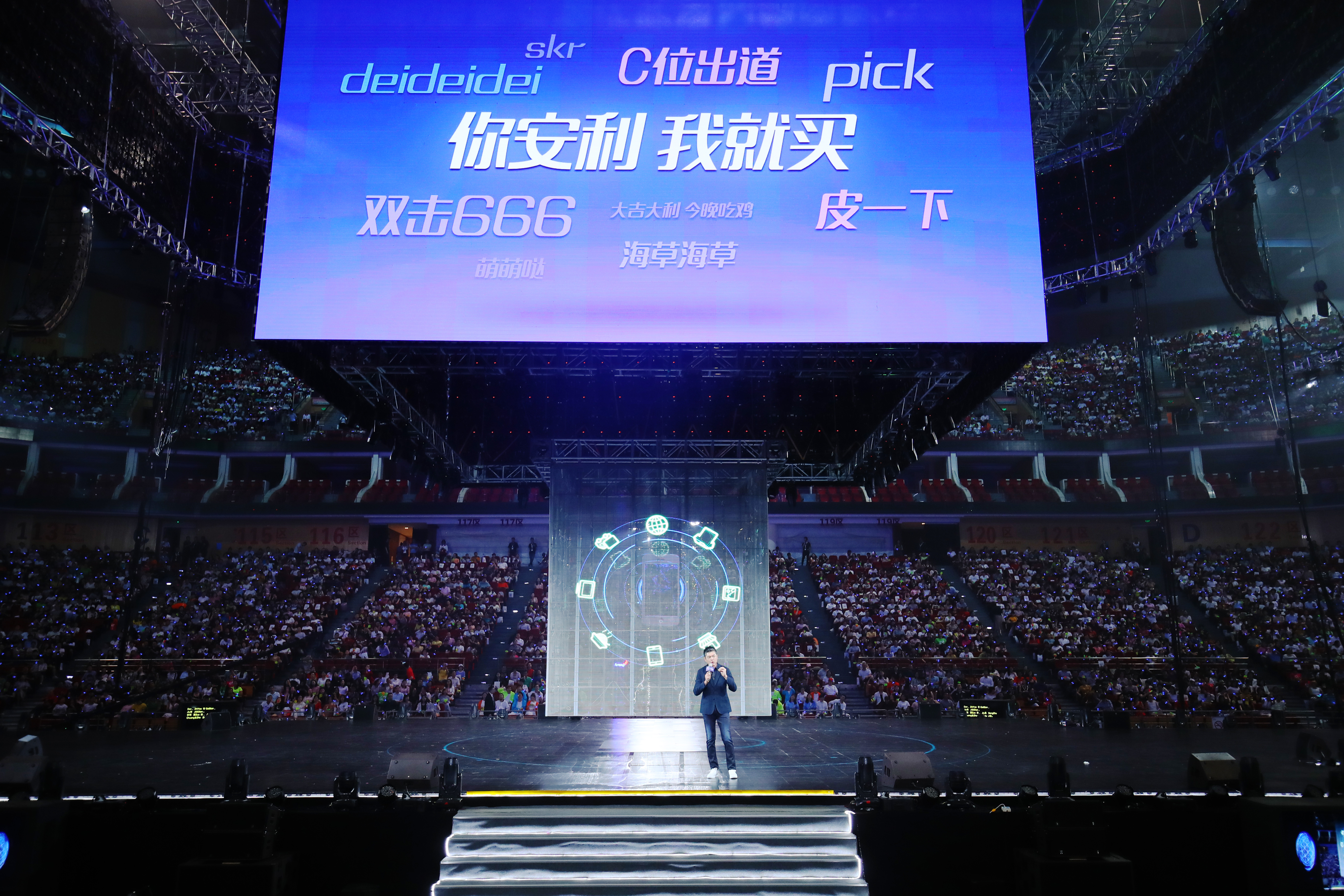 本次安利品牌活动于大型场馆举办，现场座无虚席人气高涨。舞台上方巨幕展示核心标语“你安利 我就买”及多款流行网络热词，贴合年轻语境，主讲人站在舞台中央向全场观众分享，现场氛围热烈鲜活，尽显安利品牌年轻化活力。