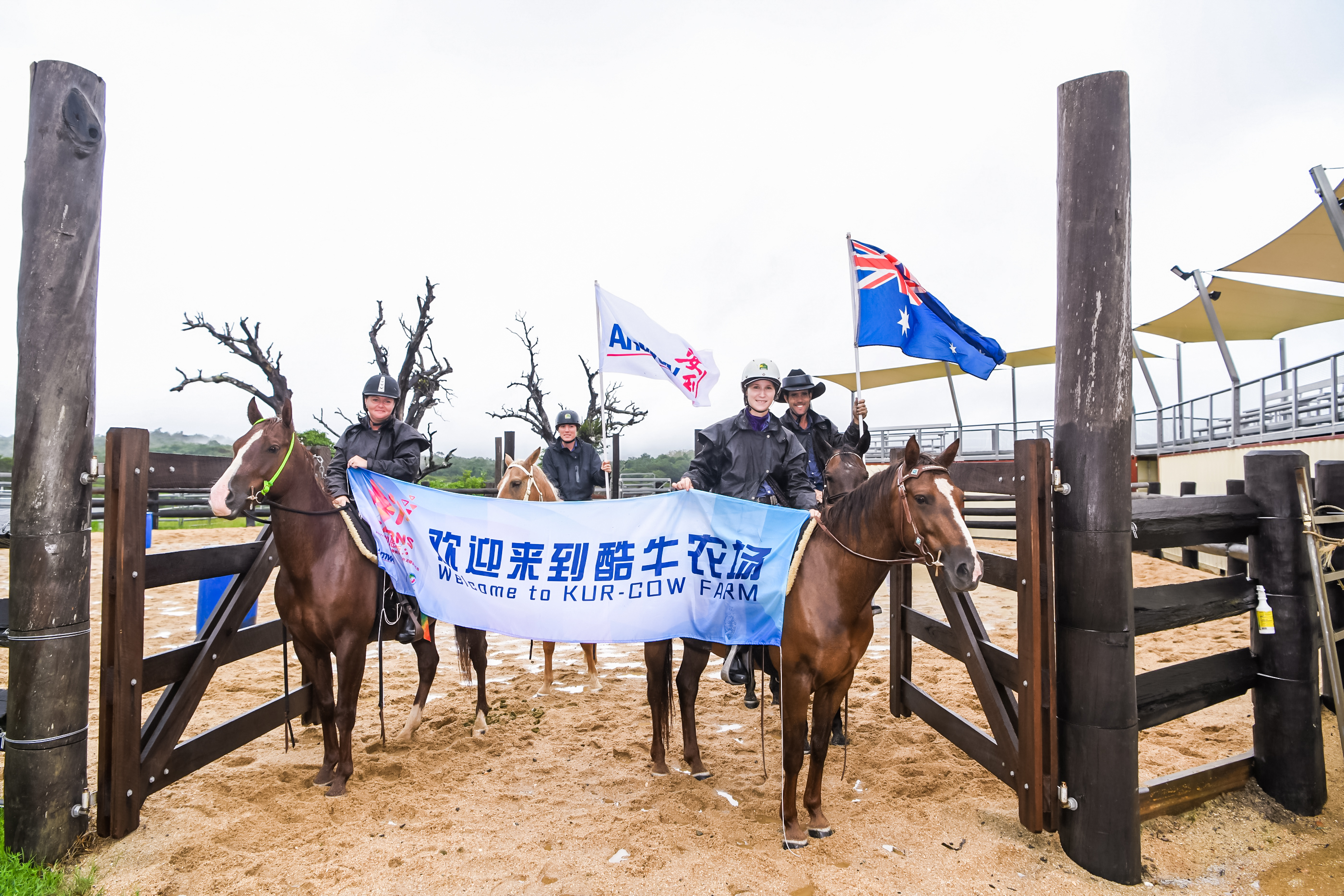 本次安利海外探访活动来到澳洲酷牛农场，骑手乘马伫立在牧场入口，举着印有“欢迎来到酷牛农场 Welcome to KUR-COW FARM”的横幅，旁侧人员分别手持安利旗帜与澳大利亚国旗，以充满当地特色的仪式热忱欢迎安利伙伴到访，氛围友好热情。