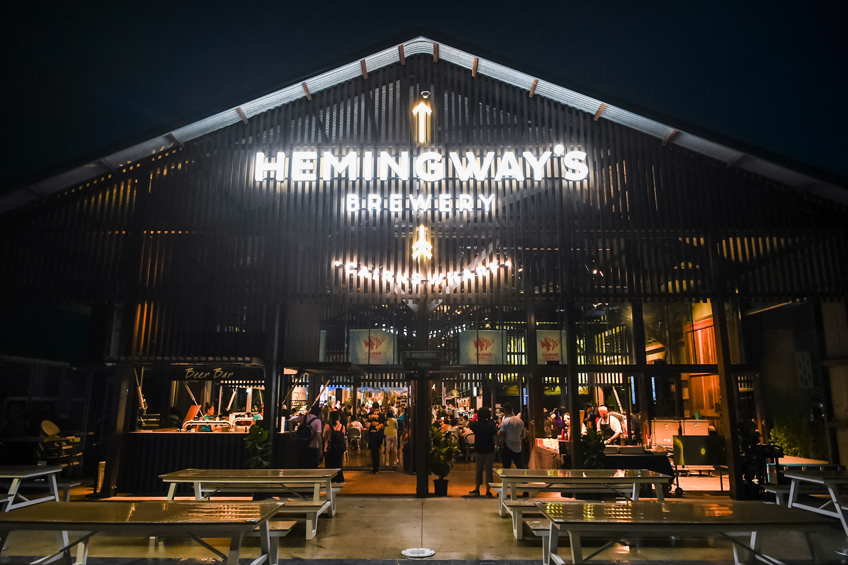 夜幕下，HEMINGWAY'S BREWERY标识明亮醒目，门店入口设置有Beer Bar与户外长桌餐位，参与活动的安利伙伴络绎不绝、有序入场，场内灯火通明，整体氛围热闹轻松，满是欢聚的愉悦气息。