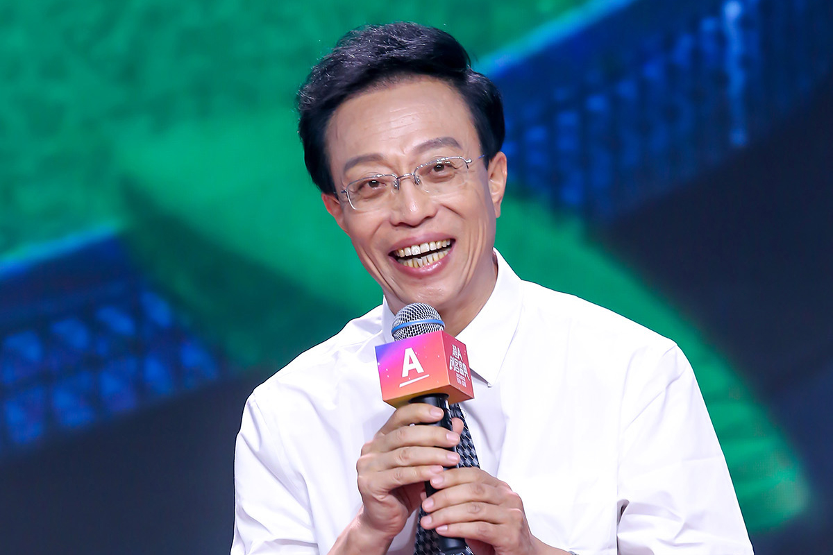 画面中身着白衬衫的嘉宾，手持印有“A”“超A创客盛典”字样的定制麦克风，面带笑意正在发言，背景为蓝绿渐变的活动大屏，现场氛围明快热烈，尽显活动积极向上的活力基调。
