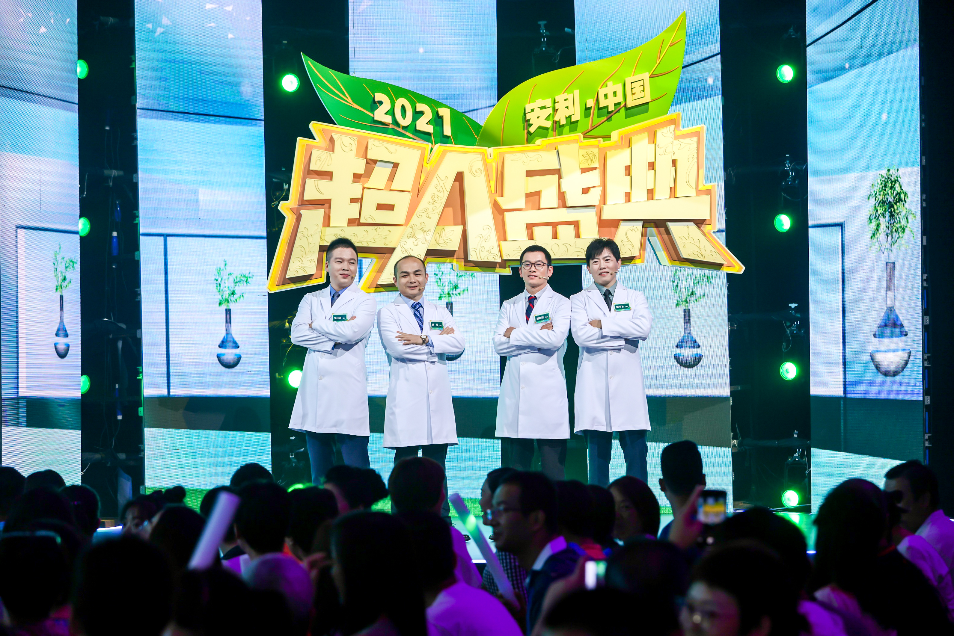 2021安利中国超A盛典活动现场，舞台背景醒目标注“2021 安利·中国 超A盛典”主题，四位身着白大褂的科研人员站姿挺拔、自信亮相，台下坐满参会观众，现场氛围热烈昂扬，尽显安利专业科研实力。