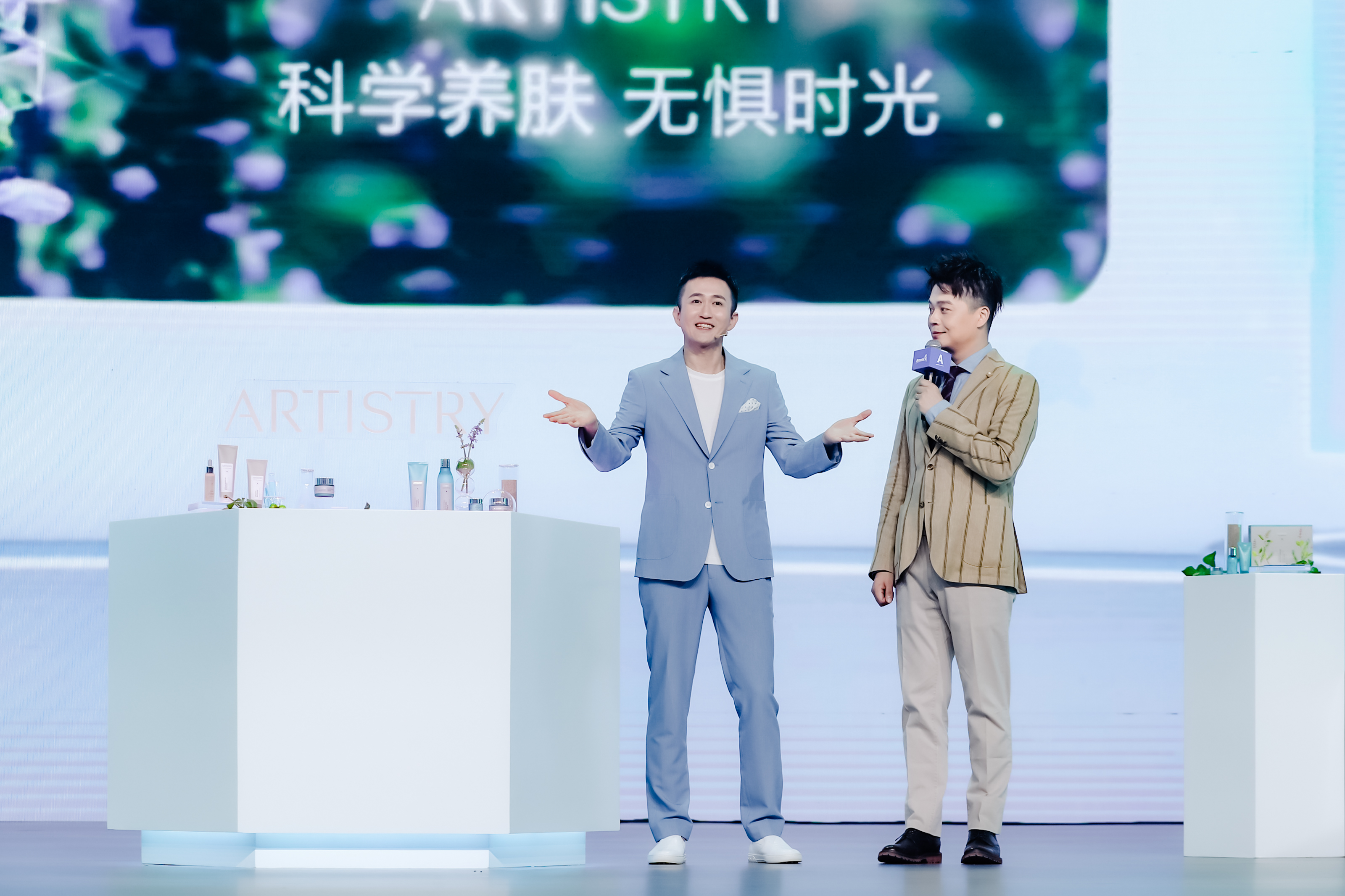 活动背景标注核心slogan“科学养肤 无惧时光”，舞台展台上陈列着ARTISTRY雅姿系列护肤产品，两位嘉宾正在台上开展护肤内容分享，现场氛围专业明快，充分传递雅姿科学护肤的品牌理念，展现安利在美护领域的专业特质。