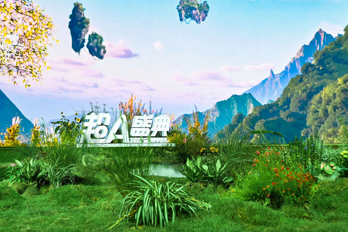 画面设有“超A盛典”白色立体字标识，周边搭配鲜绿草甸、各色花卉与迷你水洼，背景是绘有浮空仙山、连绵青峦的奇幻山水布景，整体清新鲜活、富有创意，充分彰显安利超A盛典的活力调性，氛围治愈美好。