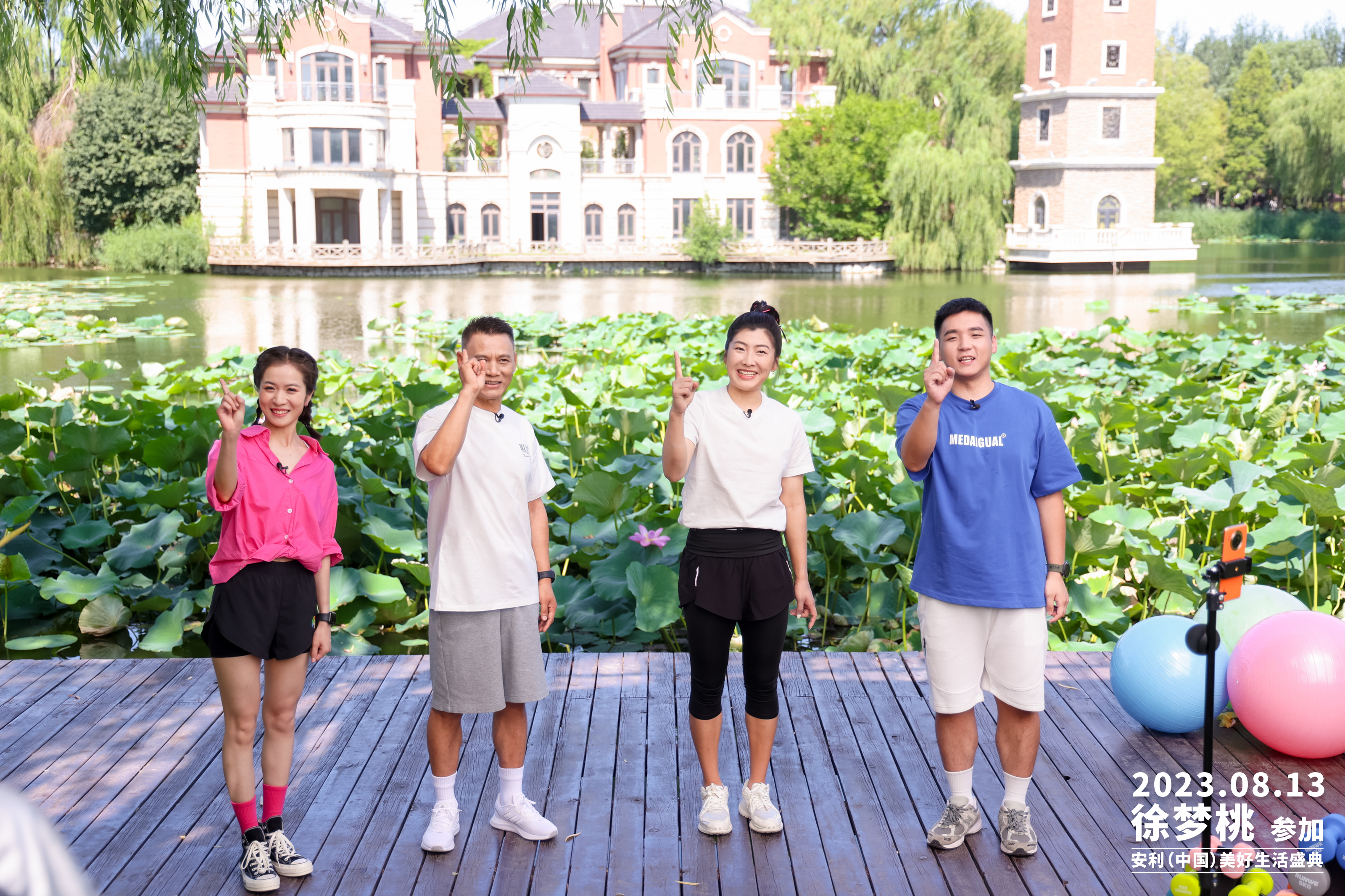 2023年8月13日，徐梦桃参加安利（中国）美好生活盛典户外活动。四人站在临湖木质平台上，周边摆放着健身用具，身后是满塘荷叶与临湖建筑，众人面带笑容活力满满，共同比出向上手势，氛围明快轻松，传递健康积极的美好生活理念。