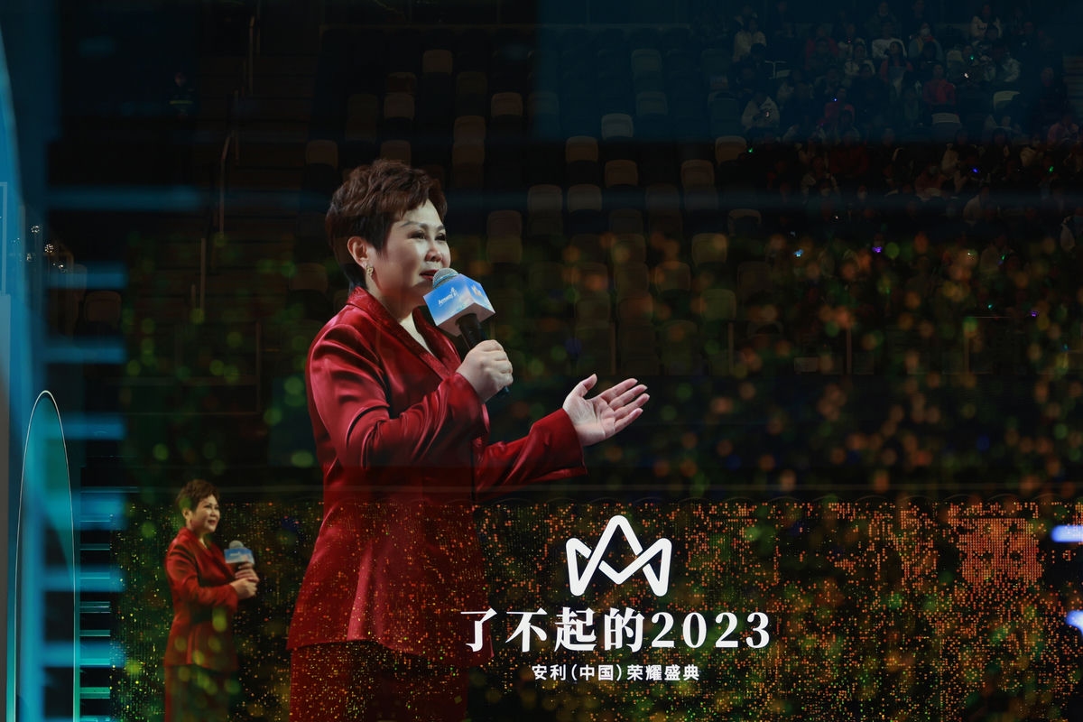 本次活动为“了不起的2023 安利（中国）荣耀盛典”，身着红色正装的发言嘉宾手持定制话筒，面向满场观众热情分享，现场光影璀璨、氛围热烈昂扬，尽显荣耀时刻的振奋感与向上气场。
