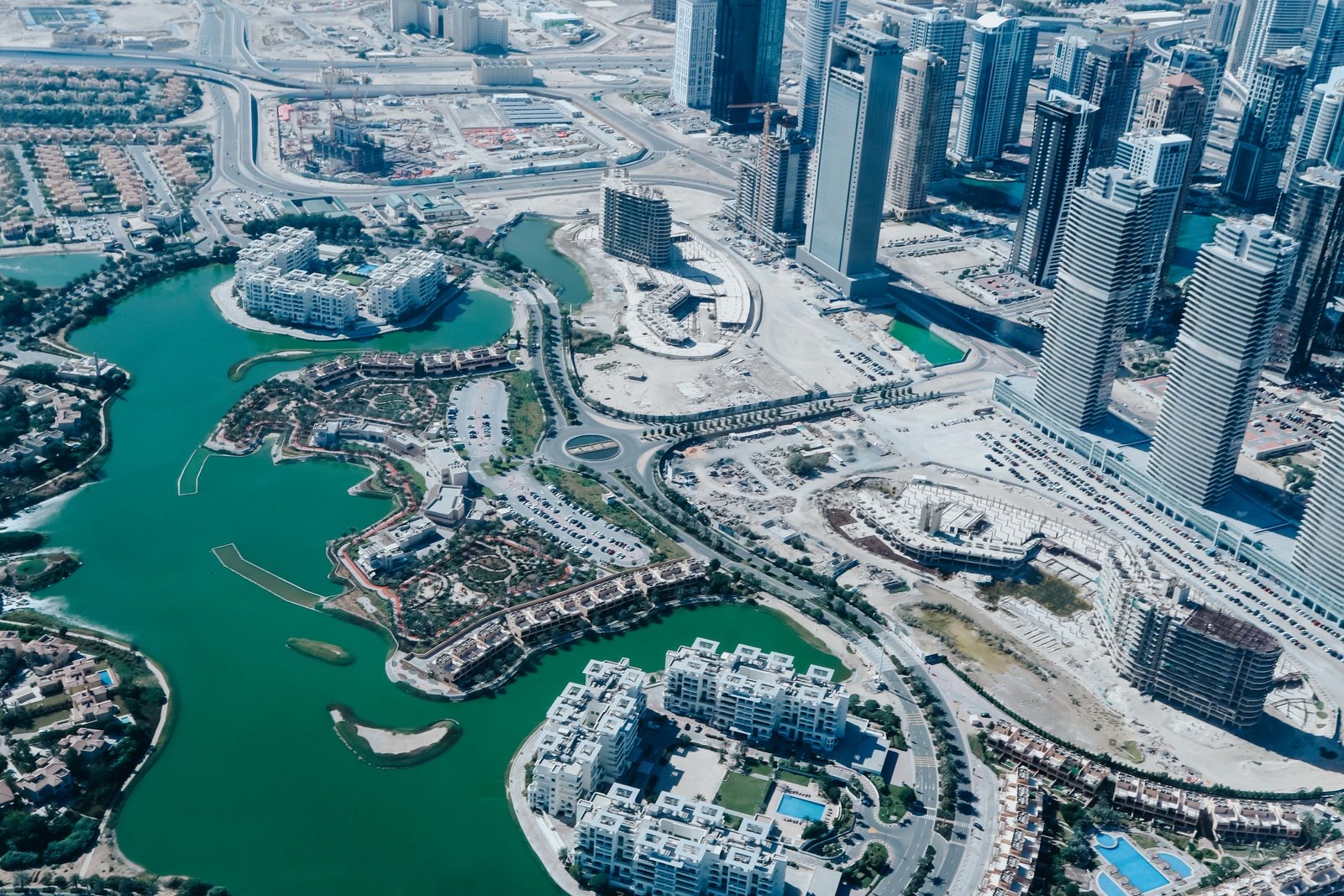 高空俯瞰迪拜城市风貌，澄澈碧色水域串联错落商住建筑群，摩天楼宇林立，道路规划规整有序，在建地块与成熟业态交相呼应，尽显城市蓬勃发展的活力，契合安利海外研讨会高端国际化的定位，传递出开阔向上的品牌氛围。