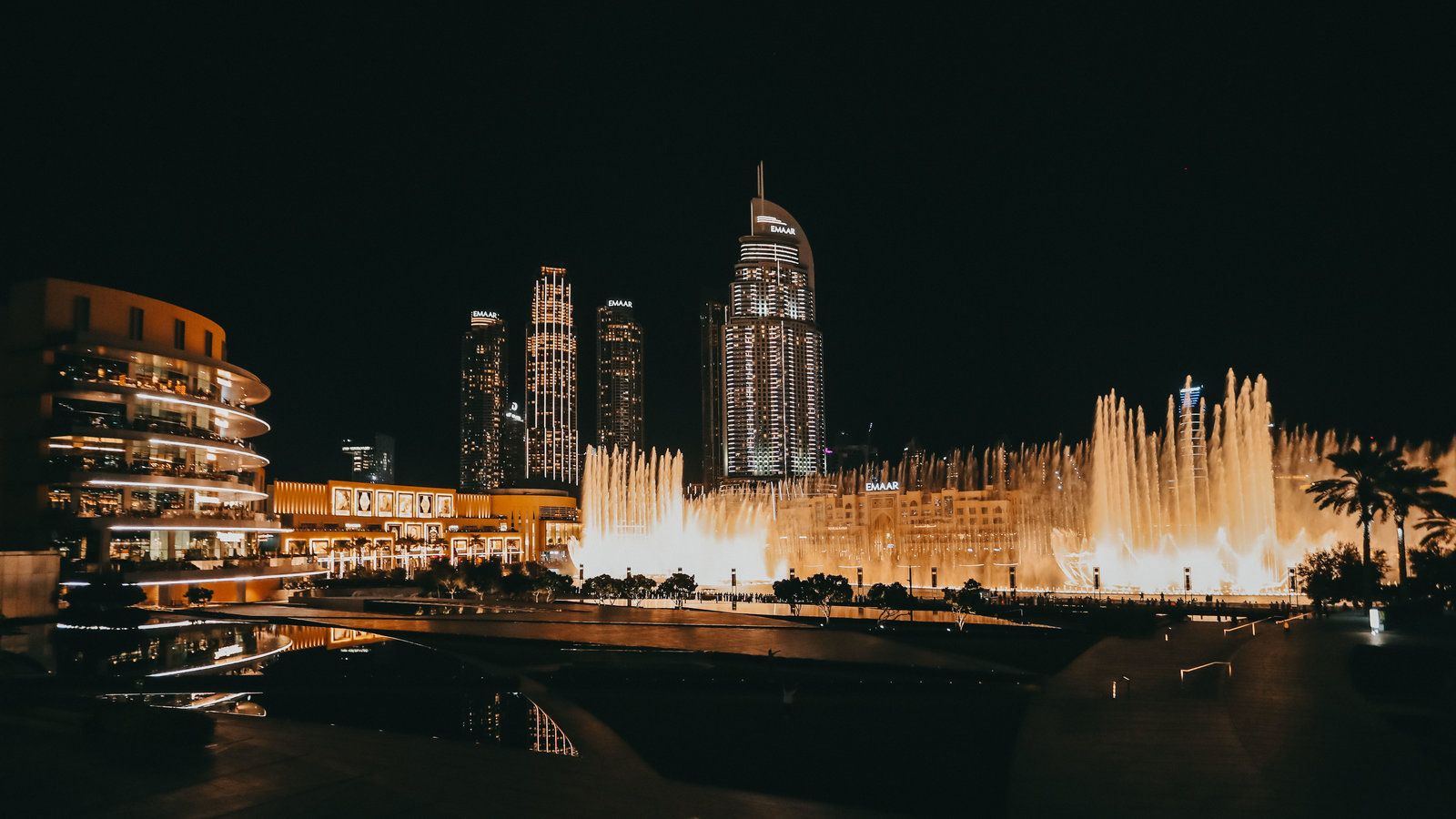 夜幕下，印有“EMAAR”字样的迪拜地标建筑群灯火通明，恢弘的音乐喷泉在暖金色灯光映照下灵动升腾，水光与建筑灯影交相辉映，氛围华丽盛大，尽显本次安利迪拜活动的高端质感与品牌实力。