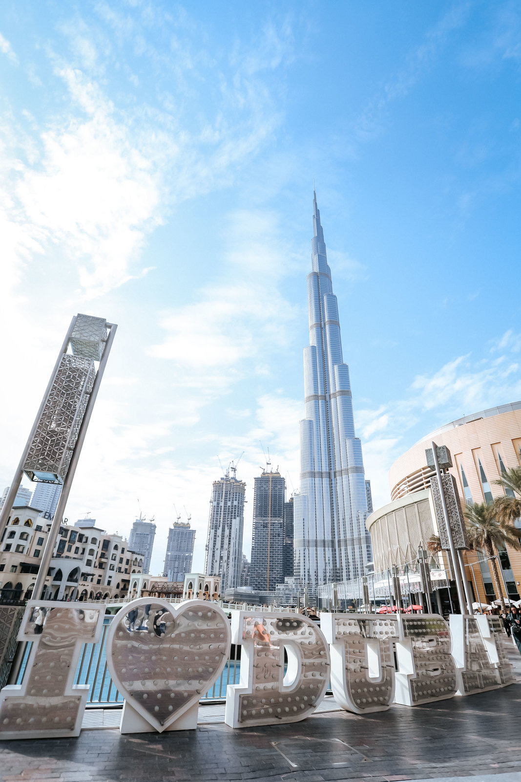 安利迪拜品牌活动开展期间，伙伴来到哈利法塔前打卡。前景处“I ❤️ DUBAI”标识醒目亮眼，远处哈利法塔高耸入云，澄澈蓝天衬着迪拜繁华的城市天际线，氛围明朗开阔，尽显本次海外行程的精彩活力，留存下伙伴们的美好行程印记。