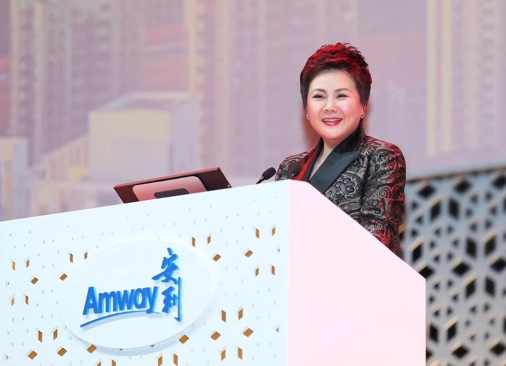 本次安利品牌活动现场，印有“Amway 安利”标识的精致讲台后，身着正装的女性发言人面带从容笑容正在发言，现场氛围正式昂扬，充分彰显安利活动积极向上的风貌，传递出共促发展的正向氛围。